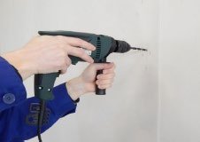Montør forborer skruehull i veggen med drill