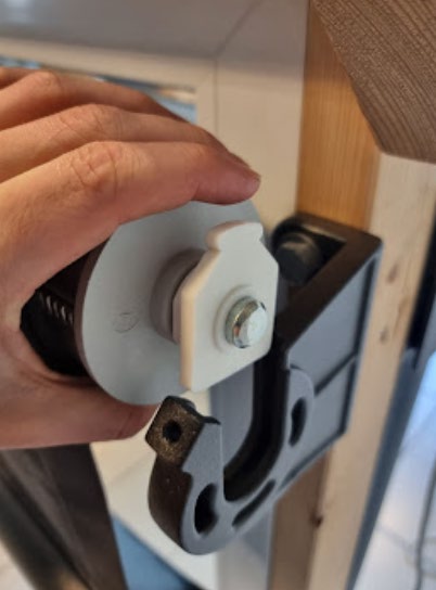 Hvit plastkomponent som gir opplagring tres inn på akselen