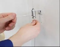 Øvre skrue løsnes forsiktig til bunnen av wirestrammeren løsner